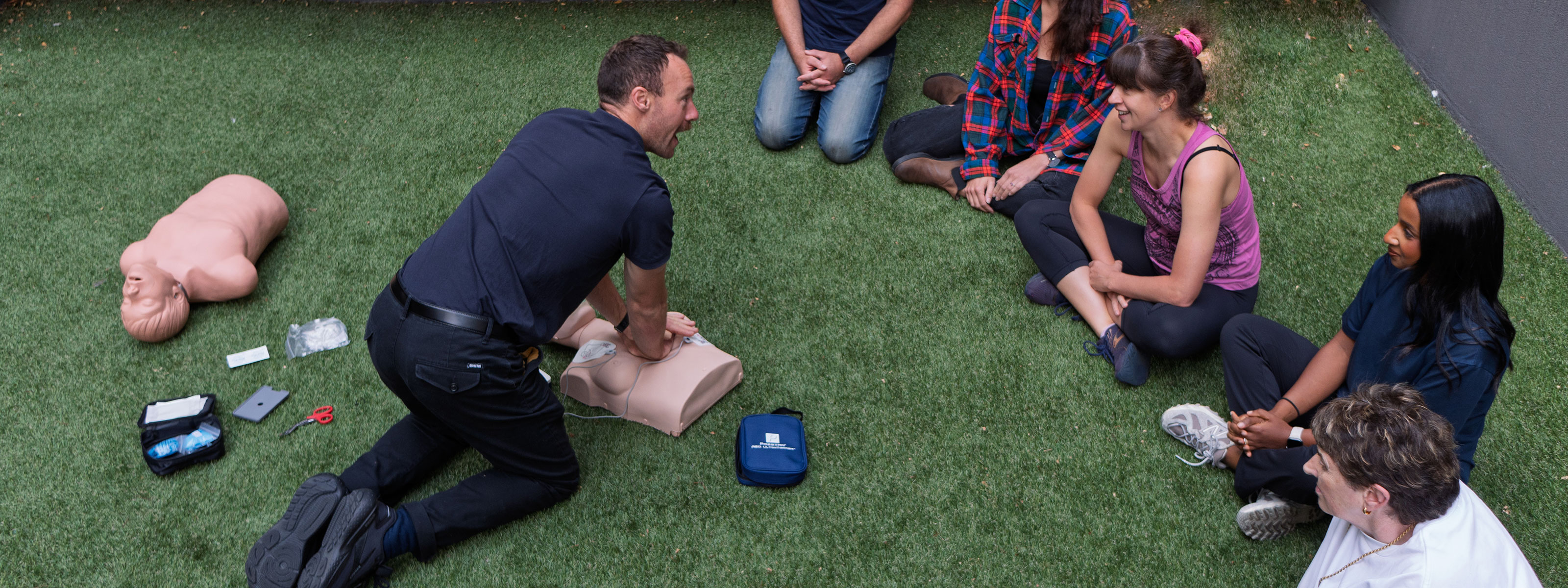 A trainer demonstrating CPR on a dummy